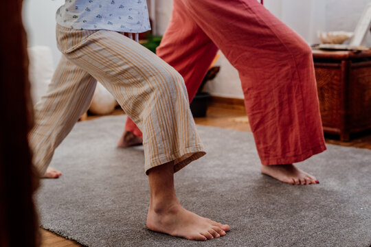 Detail of legs of grandmother and granddaughter doing yoga at room