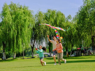 Happy family of three flying kites in the park