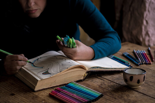 woman is doodling and colouring in her sketchbook