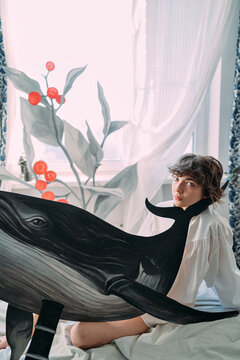 woman sitting on bed with cardboard whale