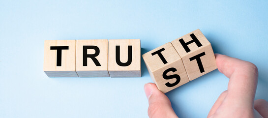 Truth instead of trust. Hand turns dice and changes the word Trust to Truth.