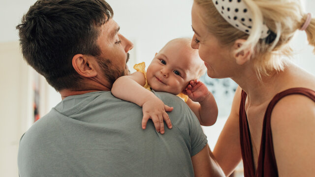 Adorable Baby Enjoying In Hugs From Caring Parents