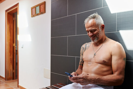 Smiling mature man texting in his bathroom