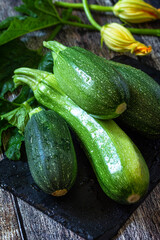 Harvesting zucchini. Healthy uncooked fresh green zucchini on a wooden kitchen table.