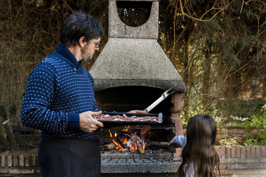 Father preparing bbq with his little daughter at garden