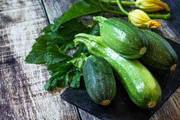 Harvesting zucchini. Healthy uncooked fresh green zucchini on a wooden kitchen table. Copy space.