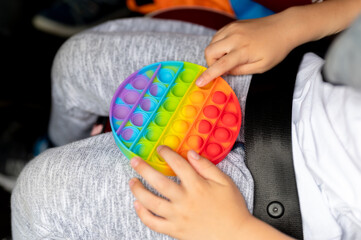 anti stress sensory pop it toys in a children's hands. a little happy kid boy plays with a simple...