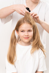 Fototapeta premium woman combs and does the hair of a little girl on a white background.