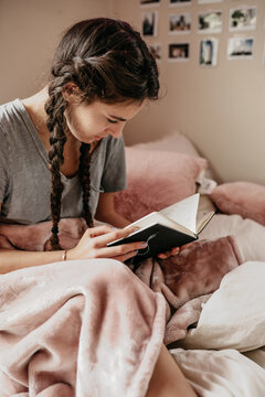 young woman reading her notebook in her bedroom
