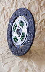 Car spare parts. Car clutch disc. Photo of a new clutch disc before installation on a car against a background of craft paper.