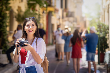 Portrait of a young tourist woman explosting the old town Plaka of Athens during her summer...