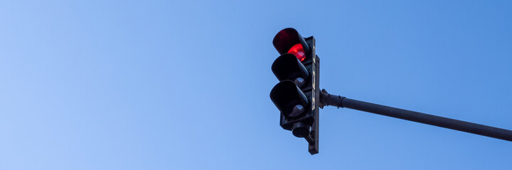 Red traffic light in front of a bright blue sky as a banner