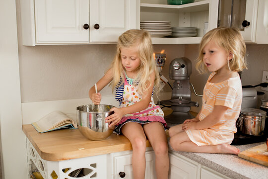 Sisters stir batter on kitchen counter