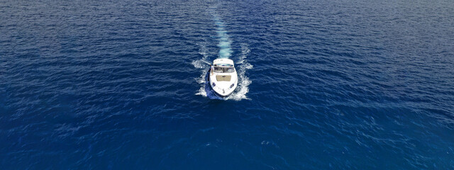 Aerial drone photo of small luxury yacht cruising in deep blue waters of Mykonos island, Cyclades,...