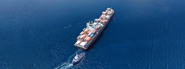 Aerial drone ultra wide panoramic photo of colourful truck size container tanker ship cruising deep blue sea near commercial port of Piraeus, Attica, Greece