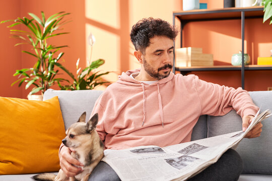 Man with newspaper and dog resting in living room
