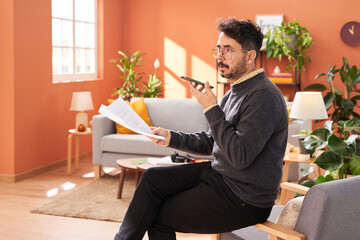 Middle aged freelancer sending voice message at home