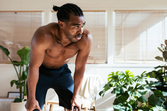 Sweaty black sportsman resting during intense workout at home