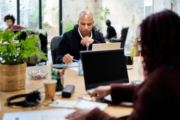 Serious man reading notes near colleagues in office