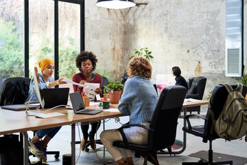 Multiethnic women discussing papers in workplace