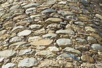 Bottom view of a watchtower's rounded wall of brown, yellow, gray cut stones held together with mortar.Stones of different shapes and sizes.Texture, background.