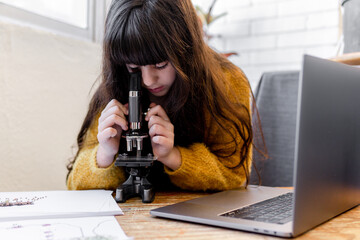 kid Girl Looking seeds with the microscope at home
