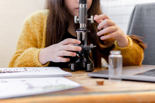 kid Girl Looking seeds Through A School Microscope at home