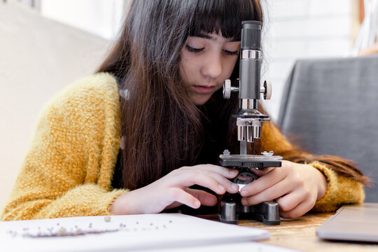 kid Girl Looking seeds in her microscope
