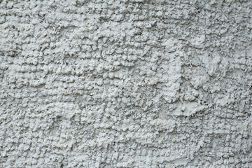 The wall is evenly covered with gray volumetric abstract rough plaster. Background, texture.