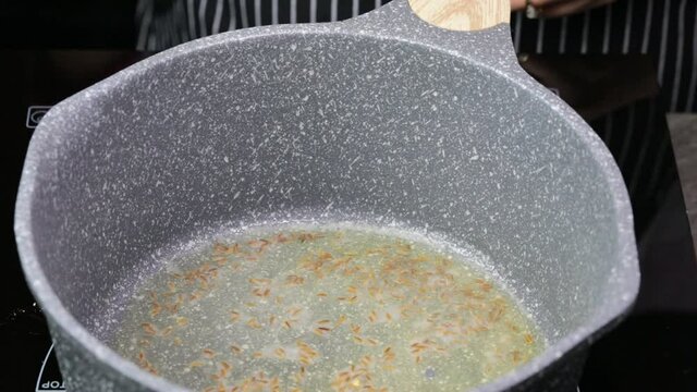 Adding cumin seeds to clarified butter or ghee for tempering or Tadka.