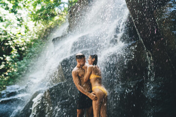 Unrecognizable man standing with woman near waterfall