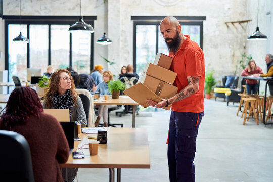 Bearded courier delivering parcels in spacious workspace