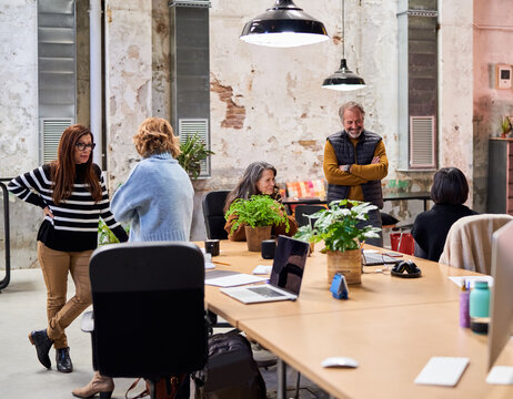 Colleagues gathering around table and speaking during break