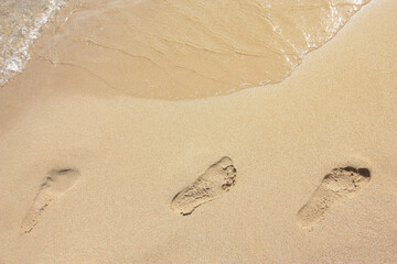 Sand with footprints and wave of the sea. High quality photo