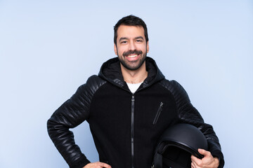 Man with a motorcycle helmet over isolated background posing with arms at hip and smiling