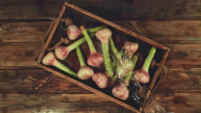 Super slow motion on the garlic pours water on a wooden background. Filmed on a high-speed camera at 1000 fps. High quality FullHD footage