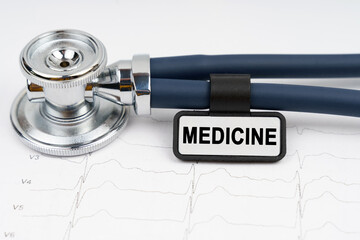 On the cardiogram is a stethoscope and a plate with the inscription - MEDICINE