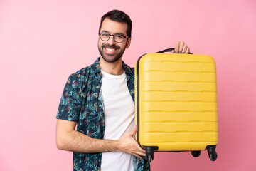 Young caucasian man over isolated background in vacation with travel suitcase