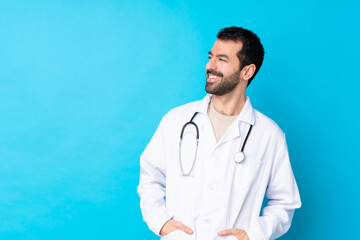 Young caucasian man over isolated background wearing a doctor gown and with stethoscope