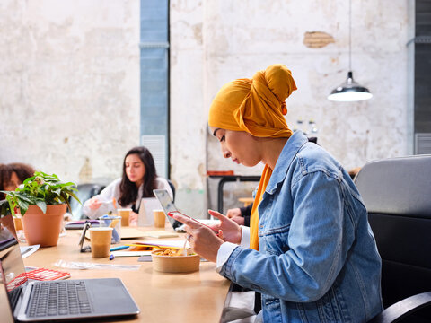 Muslim employee using smartphone during lunch break