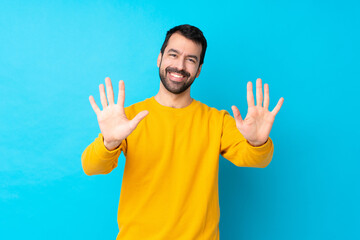 Young caucasian man over isolated blue background counting ten with fingers