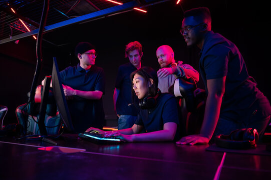 A cyber team of guys and a coach explains their strategy to a new team member an asian girl