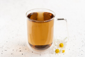 Chamomile tea and chamomile in glass mug on white cement table. Herbal tea. Top view. Flat lay
