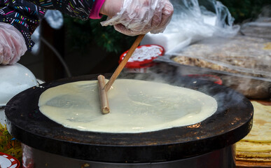 Preparing delicious crepes pancakes on the street food market festival fair
