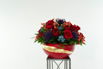 Mix of red, blue and pink flowers arrangement in red vase. 