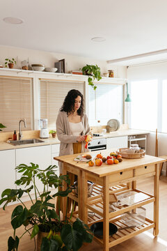 Young housewife cooking healthy food in kitchen