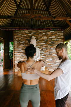 Male Yoga Teacher Helping Female Student