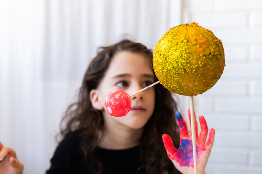 Portrait of little girl observing her solar system project with glitter on the face