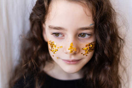 Little girl with golden glitter of stars on her face