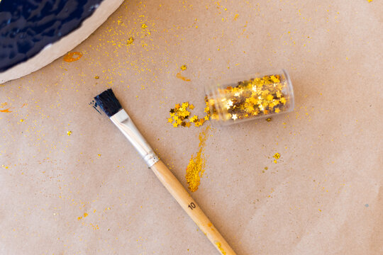Top view of small golden stars and brushes to make crafts at home